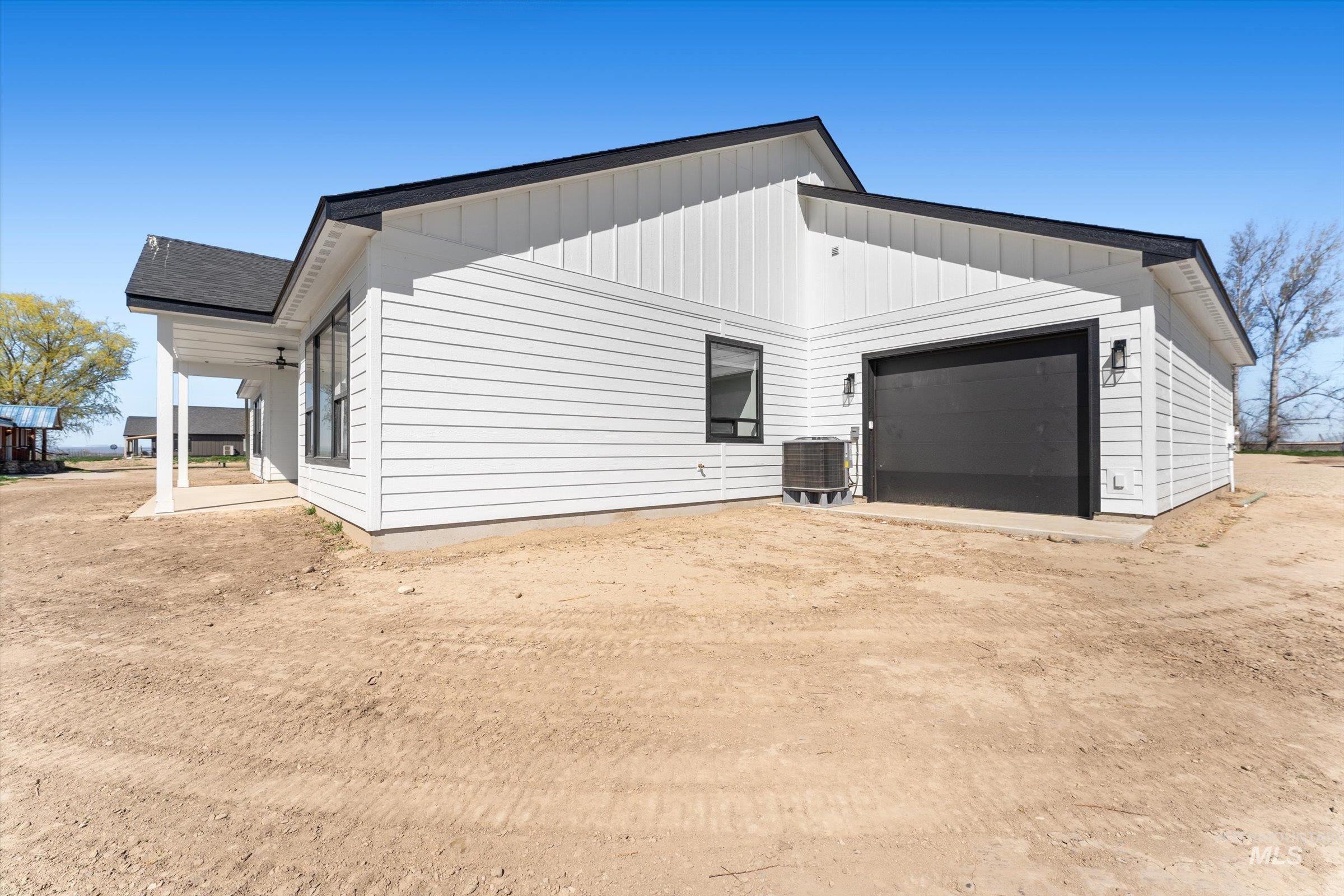 26219 Reed Lane Wilder, ID 83676 - Photo 34 of 35 View of property exterior featuring a garage, dirt driveway, and board and batten siding