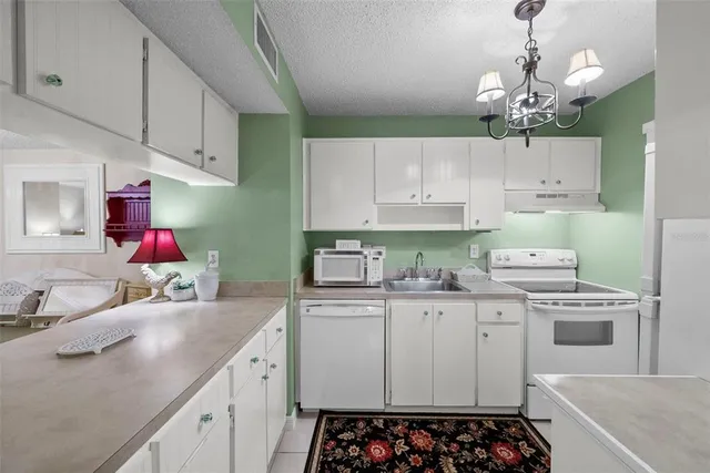 a kitchen with stainless steel appliances granite countertop a refrigerator a sink a stove and a refrigerator