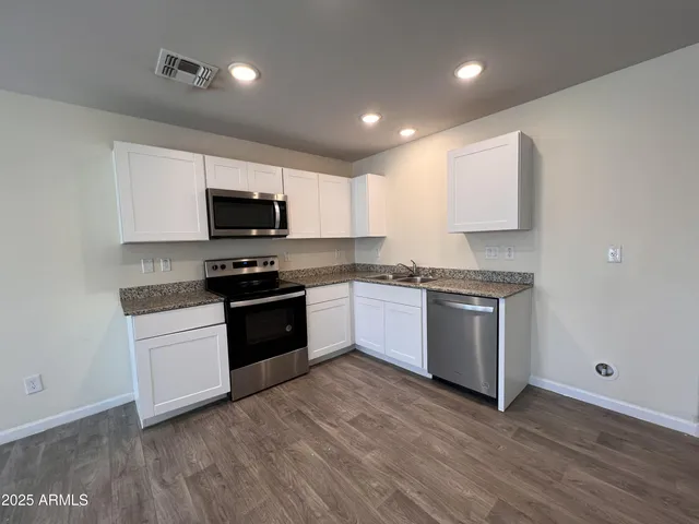 a kitchen with granite countertop a refrigerator and a stove top oven