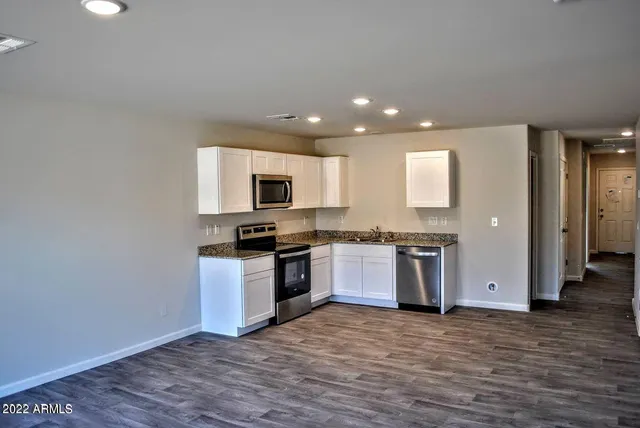 a kitchen with granite countertop a sink cabinets and stainless steel appliances