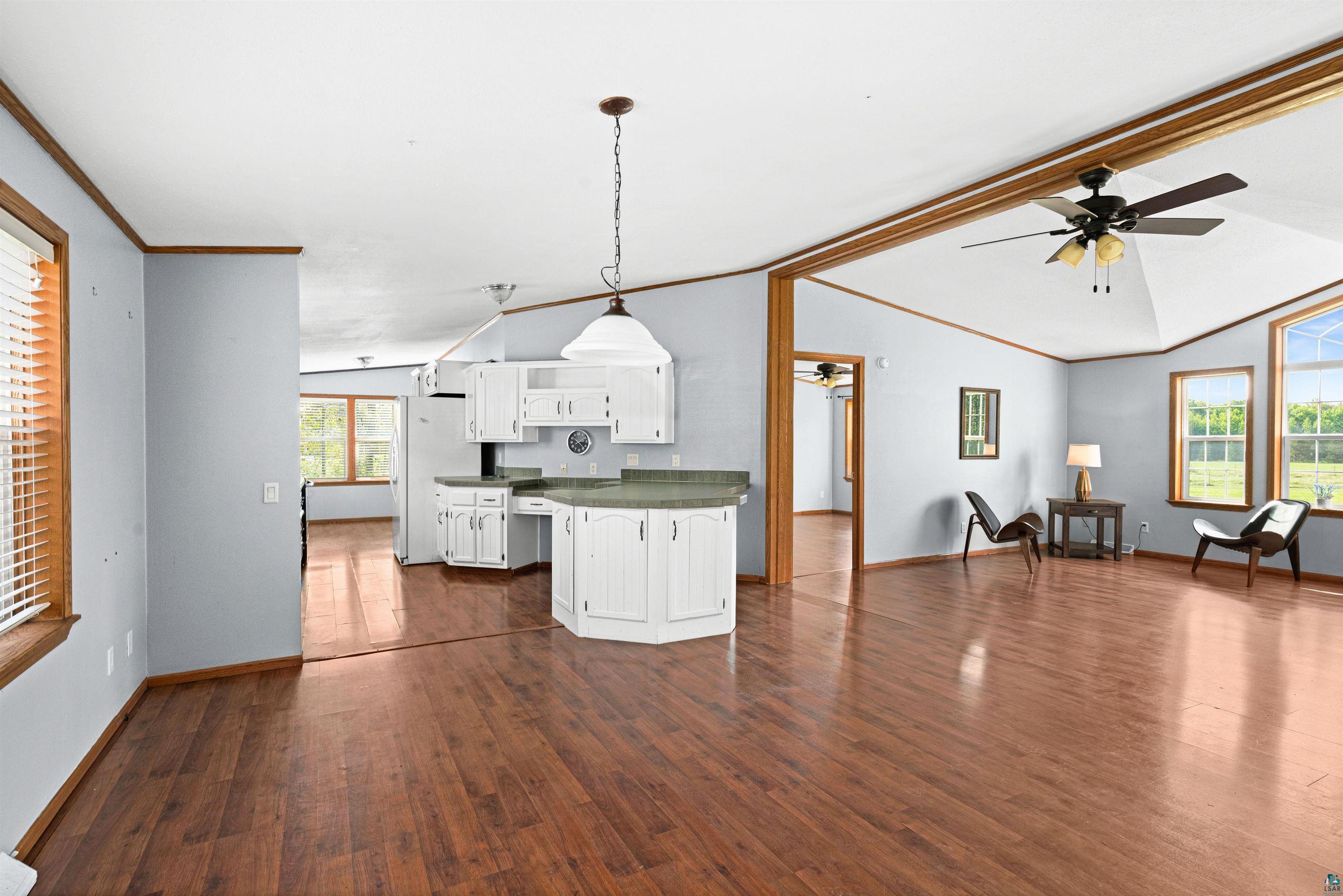 3126 Beyer Road Duluth, MN 55804 - Photo 11 of 23 Open-concept dining/living area with laminate flooring, vaulted ceilings, and a kitchen featuring white cabinetry and light-colored countertops