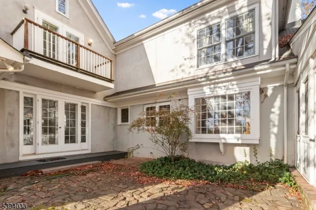 a view of a white house next to a yard with large trees