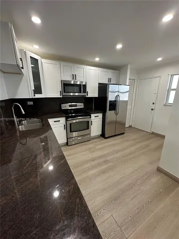 a kitchen with stainless steel appliances kitchen island granite countertop a stove and a sink