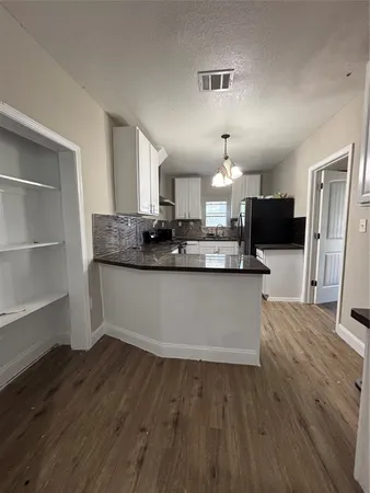 a large kitchen with granite countertop a large counter top appliances and cabinets