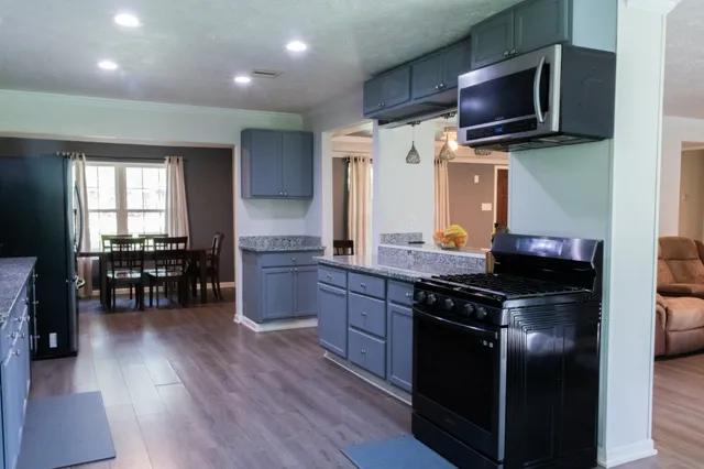 a kitchen with stainless steel appliances granite countertop a stove and a wooden floors
