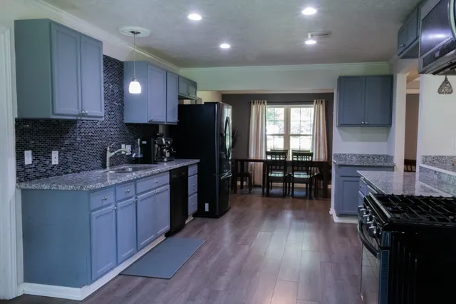 a kitchen with wooden floors wooden cabinets a counter top space and stainless steel appliances