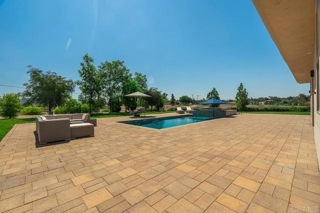 a view of swimming pool with seating space and trees in the background