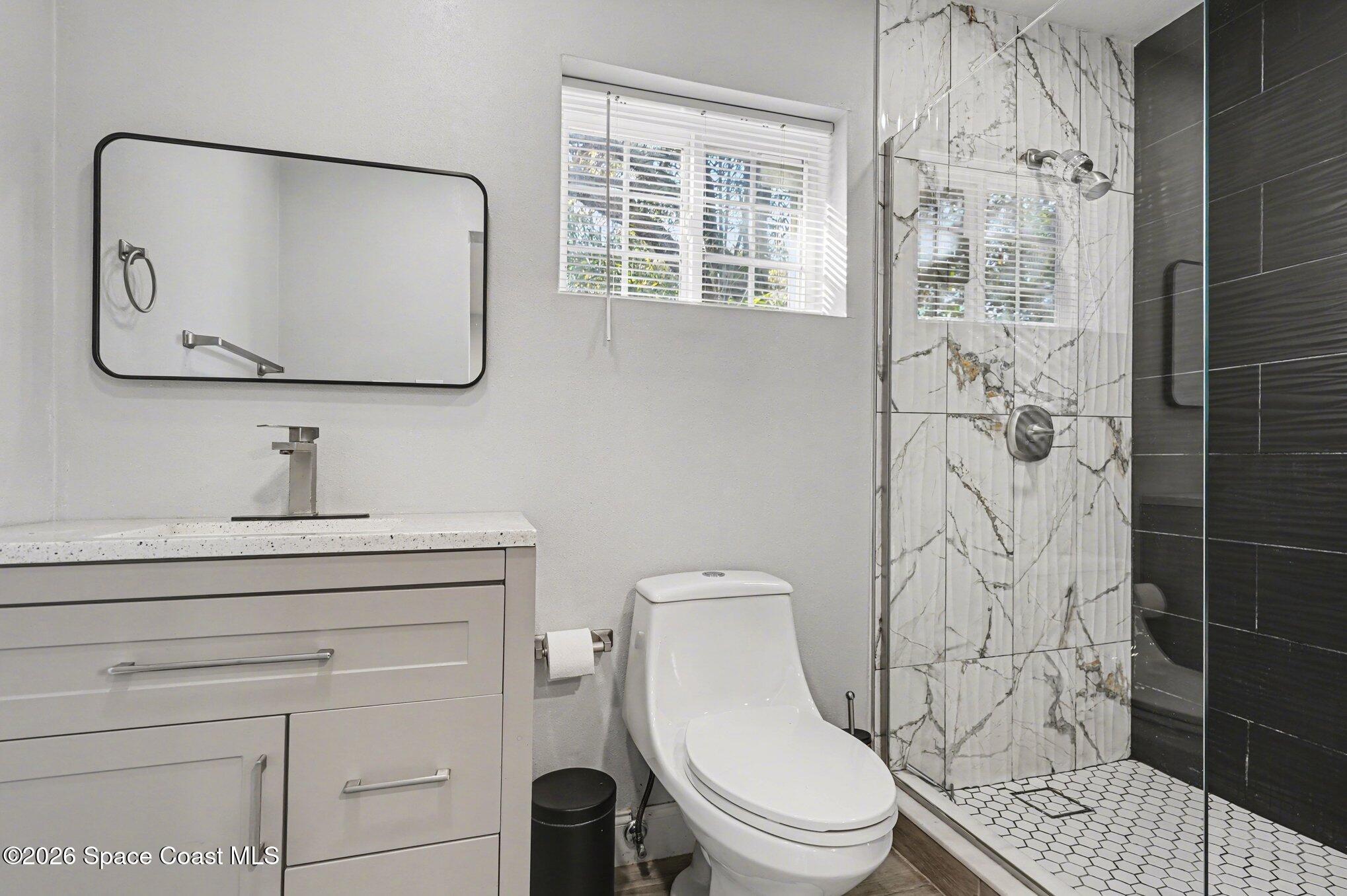 809 Espanola Way Melbourne, FL 32901 - Photo 22 of 27 a bathroom with a toilet sink vanity and mirror