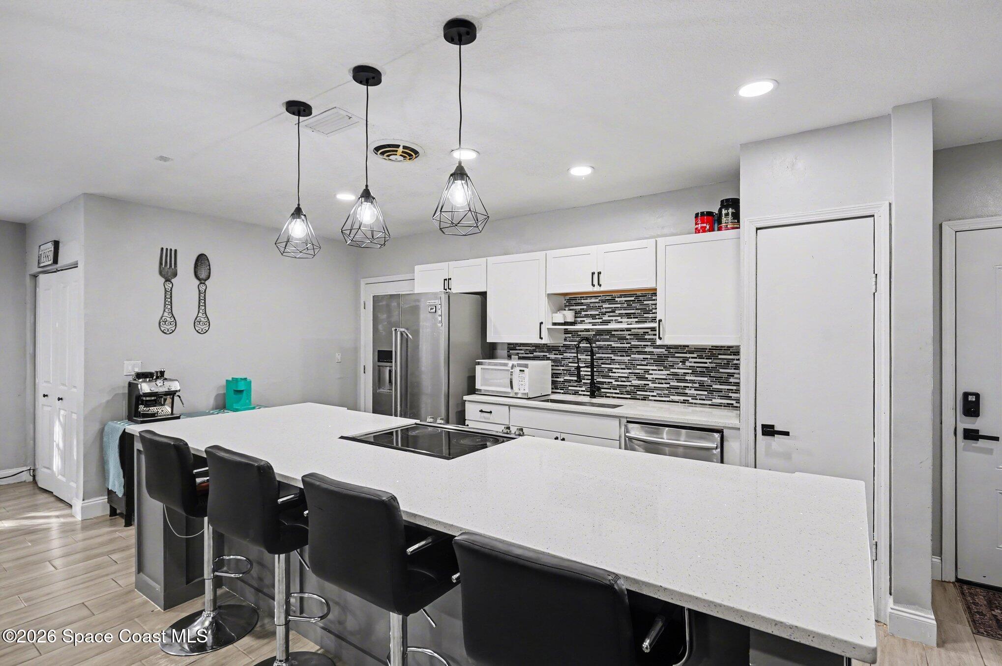809 Espanola Way Melbourne, FL 32901 - Photo 8 of 27 a kitchen with stainless steel appliances kitchen island granite countertop a table chairs and a refrigerator