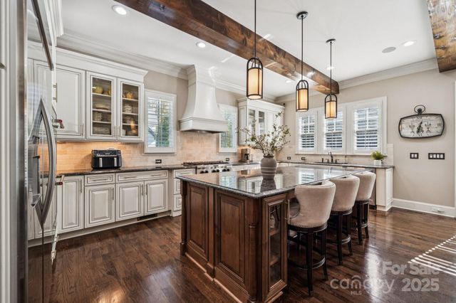 a kitchen with stainless steel appliances granite countertop a sink a stove a refrigerator cabinets and dining table with wooden floor