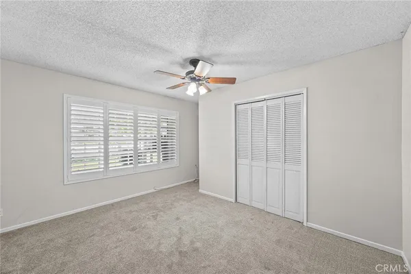 an empty room with a window and a fan
