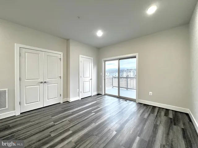 a view of an empty room with wooden floor and closet