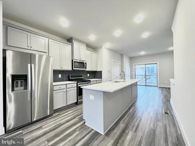 a large kitchen with a center island wooden floor stainless steel appliances and cabinets