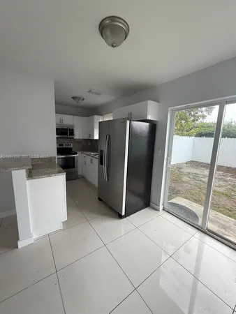 a kitchen with stainless steel appliances granite countertop a refrigerator a sink a stove top oven and a large window