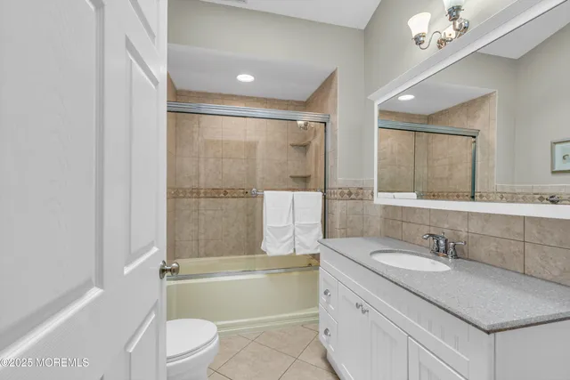 a bathroom with a granite countertop sink a mirror a toilet and bathtub