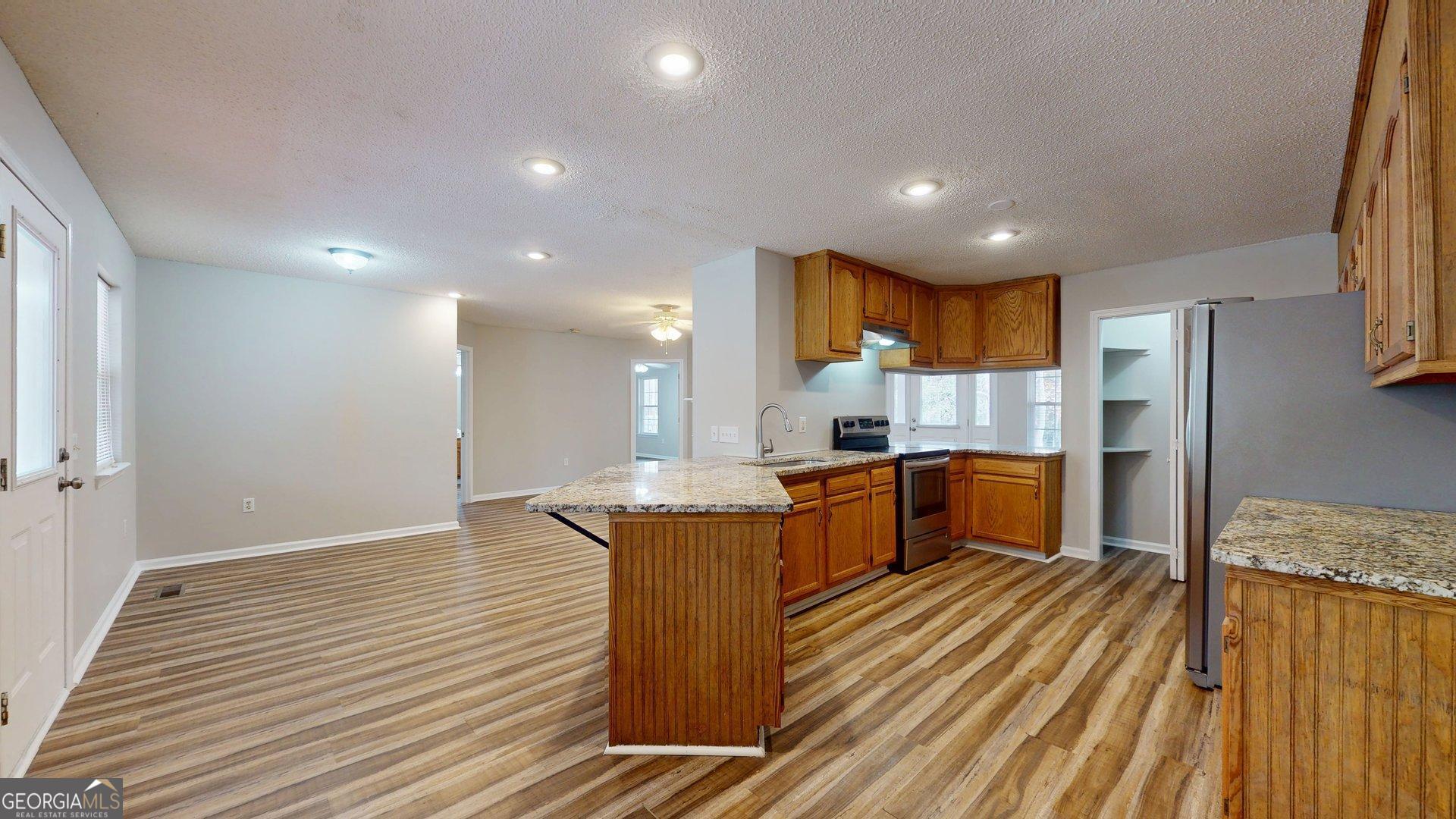 125 Harden Road Statesboro, GA 30458 - Photo 20 of 35 a kitchen with stainless steel appliances granite countertop a refrigerator a sink dishwasher a stove and white countertops with wooden floor