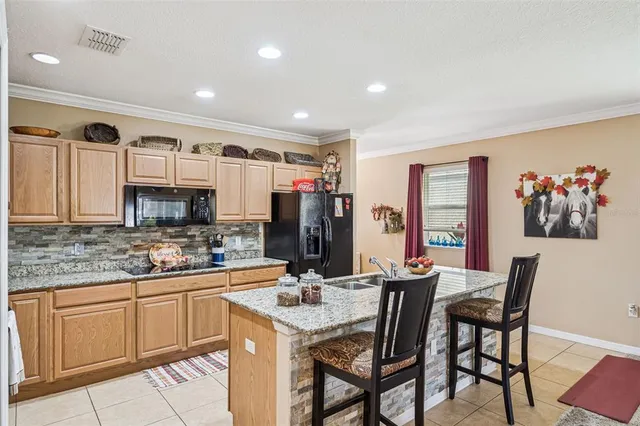 a kitchen with a sink a refrigerator and chairs