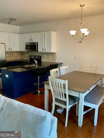 a kitchen with a dining table chairs stainless steel appliances and cabinets