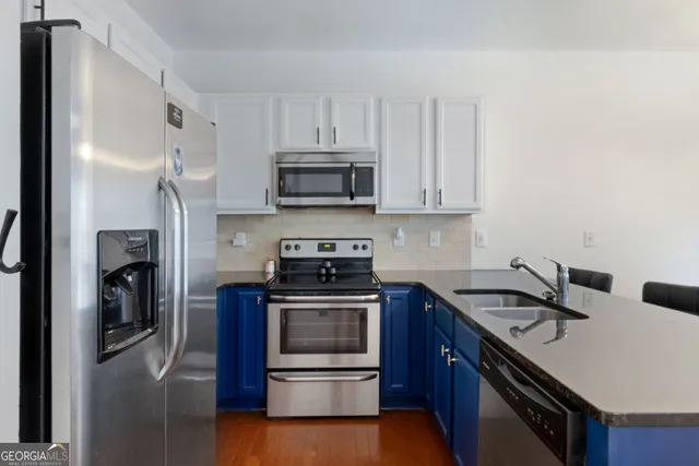 a kitchen with stainless steel appliances a sink a stove a microwave and cabinets