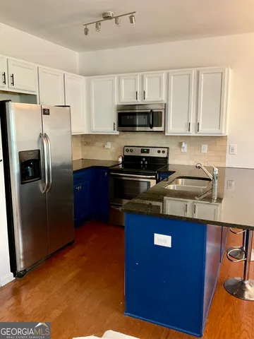 a kitchen with stainless steel appliances granite countertop a refrigerator a stove a sink a microwave and a refrigerator