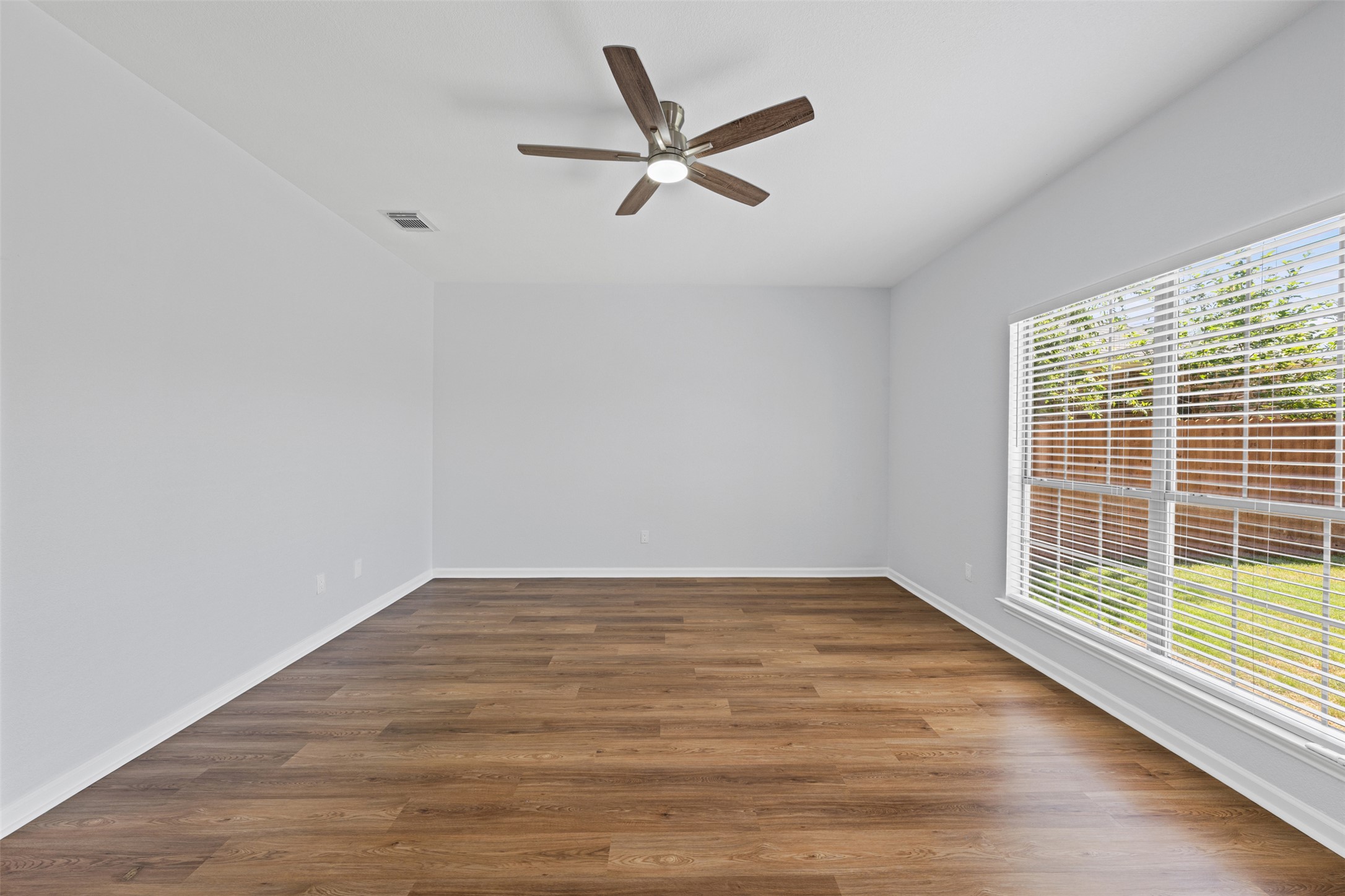 243 Engineers Pass Jarrell, TX 76537 - Photo 13 of 40 Spacious interior featuring wood-finish flooring, a large window with horizontal blinds, and a contemporary ceiling fan