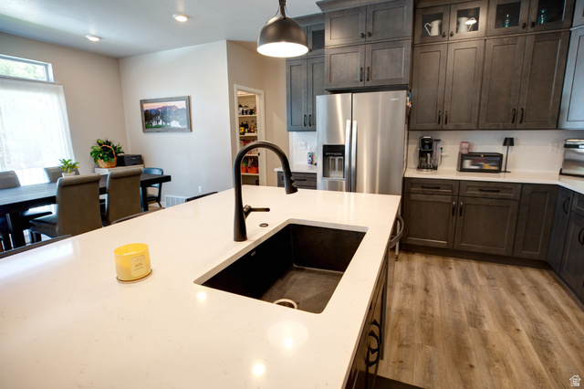 983 South 950 West Provo, UT 84601 - Photo 8 of 56 Kitchen featuring a large island with an undermount sink and matte black faucet, wood-finish flooring, dark-toned cabinetry, stainless steel refrigerator, and recessed lighting