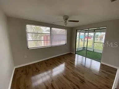 a view of an empty room with wooden floor and a window
