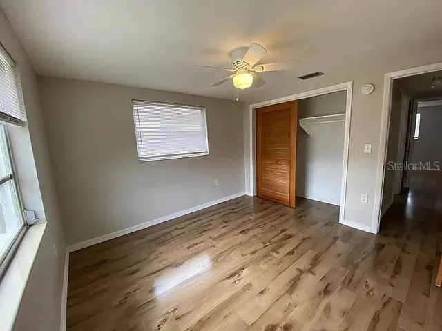a view of an empty room with wooden floor and a window
