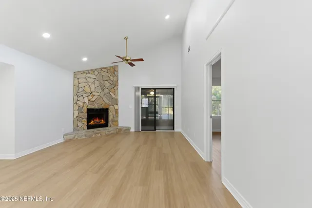 an empty room with wooden floor fireplace and windows