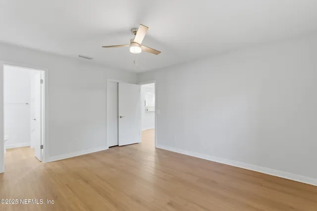 an empty room with wooden floor and ceiling fan