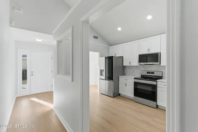 a view of kitchen with stainless steel appliances granite countertop a refrigerator and a stove top oven