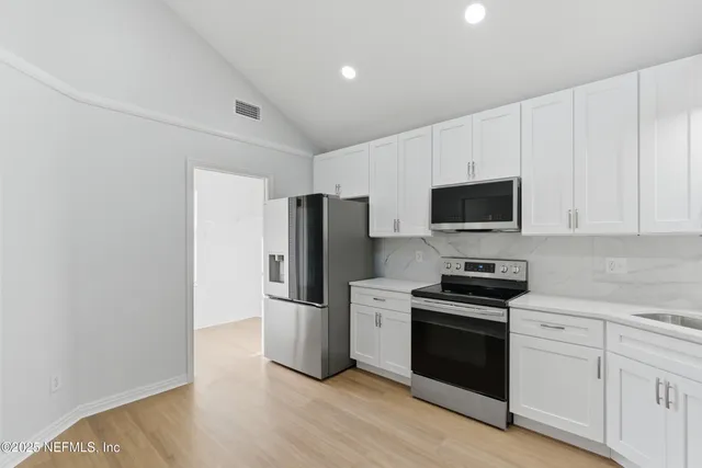a kitchen with a refrigerator stove and white cabinets