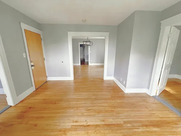 a view of a hallway with wooden floor and cabinet