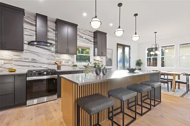 a kitchen with stainless steel appliances granite countertop a stove a sink a oven a dining table and chairs