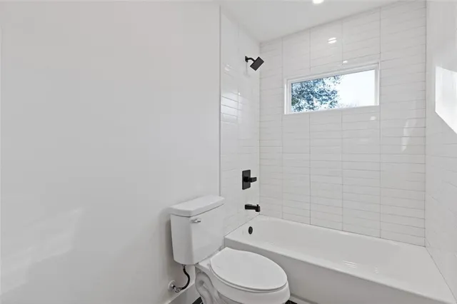 a white toilet and tub next to a window