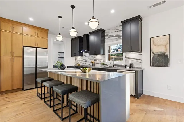 a kitchen with stainless steel appliances kitchen island granite countertop a sink a refrigerator and a refrigerator