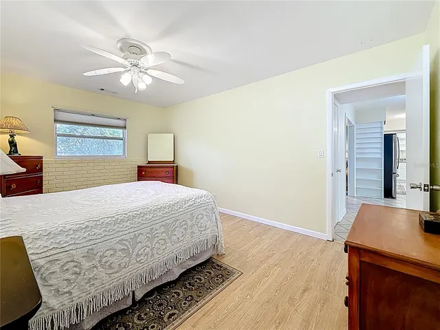 a view of an empty room with wooden floor and a ceiling fan