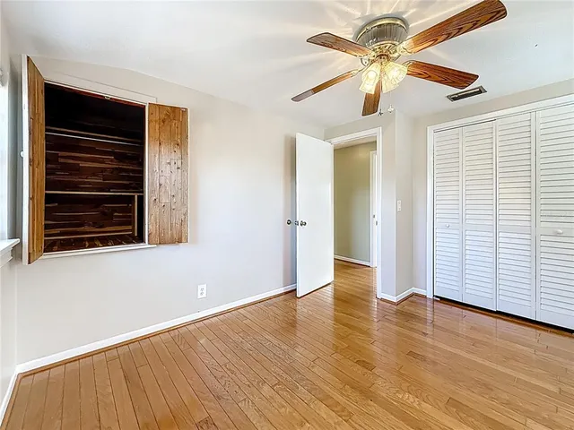 a view of empty room with wooden floor and fan