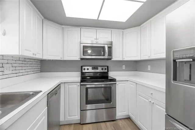 a kitchen with white cabinets and stainless steel appliances