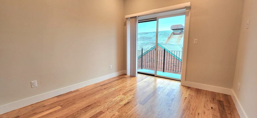 58 Lubec Street, Unit 8 Boston, MA 02128 - Photo 11 of 16 a view of an empty room with wooden floor and a window