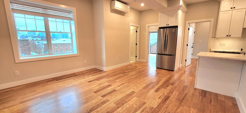 58 Lubec Street, Unit 8 Boston, MA 02128 - Photo 5 of 16 a view of a kitchen with a refrigerator a stove top oven and wooden floor