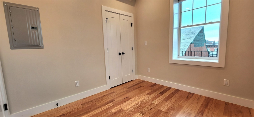 58 Lubec Street, Unit 8 Boston, MA 02128 - Photo 8 of 16 an empty room with a window and wooden floor