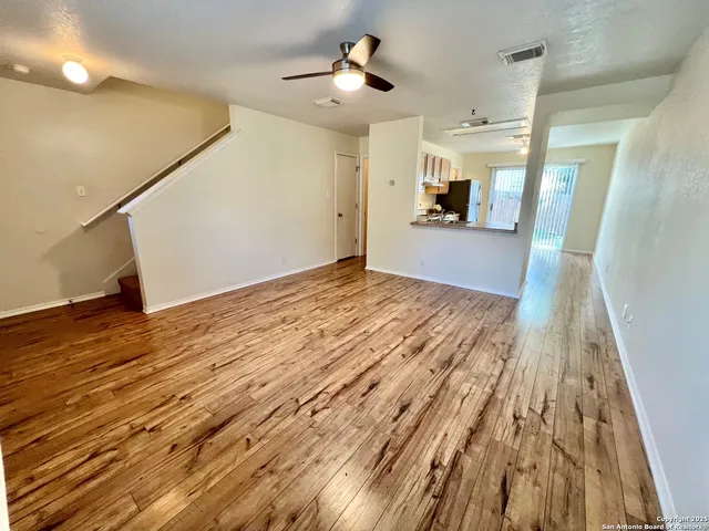 a view of a big room with wooden floor and a kitchen