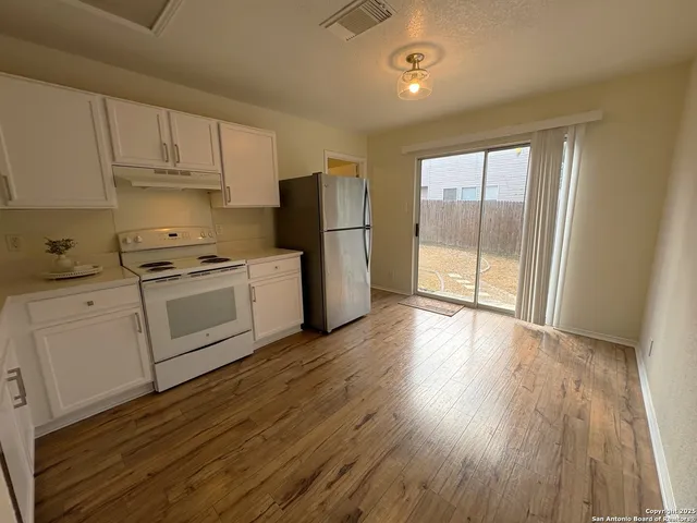 a kitchen with wooden floors and white stainless steel appliances