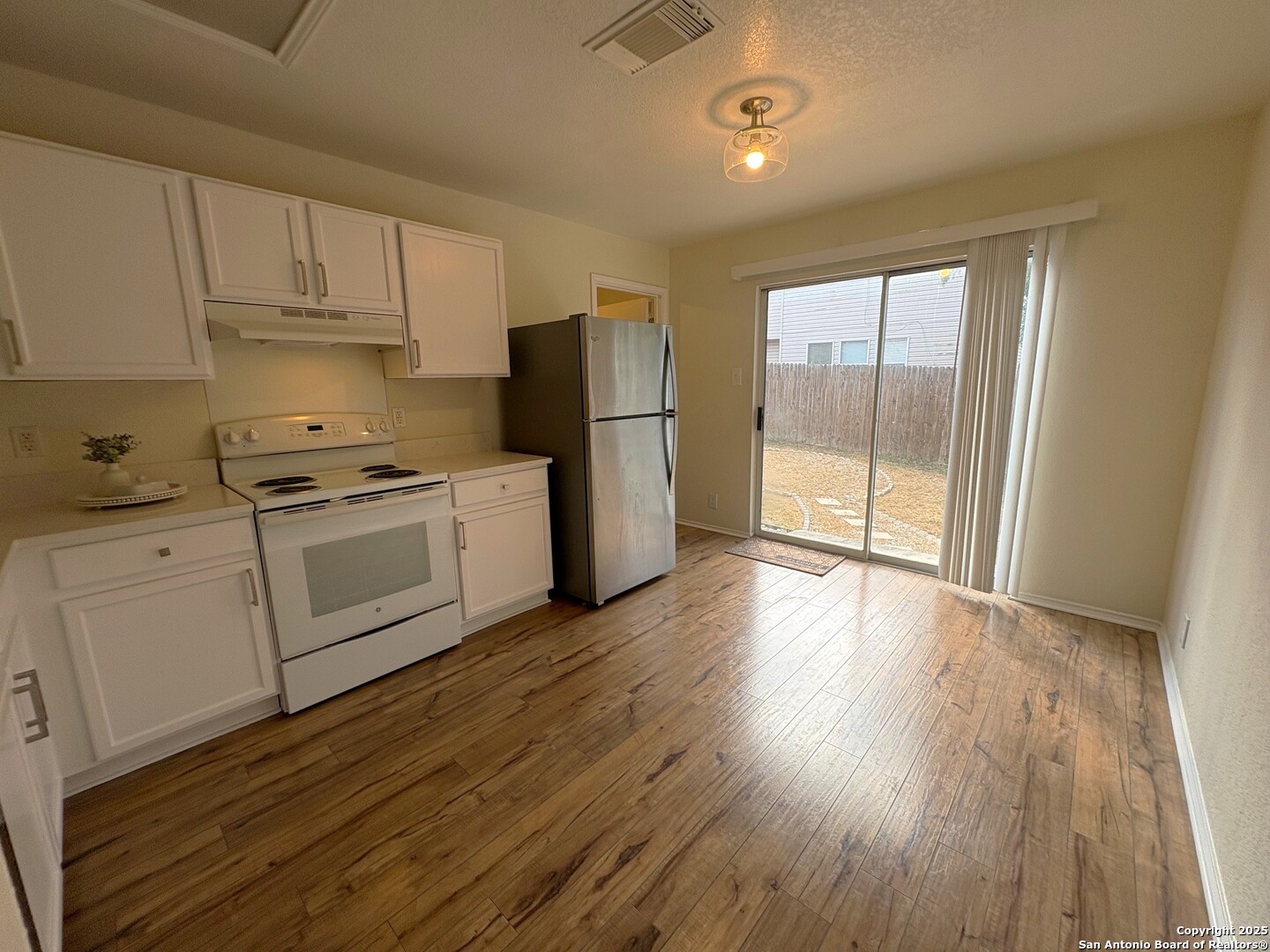 10134 Ranger Canyon San Antonio, TX 78251 - Photo 10 of 22 a kitchen with wooden floors and white stainless steel appliances