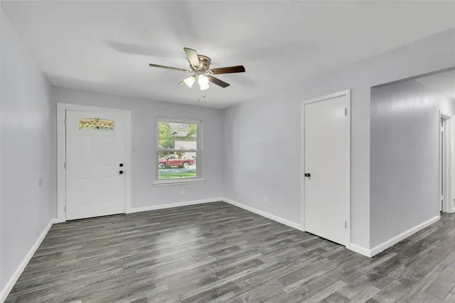 a view of an empty room with window and wooden floor