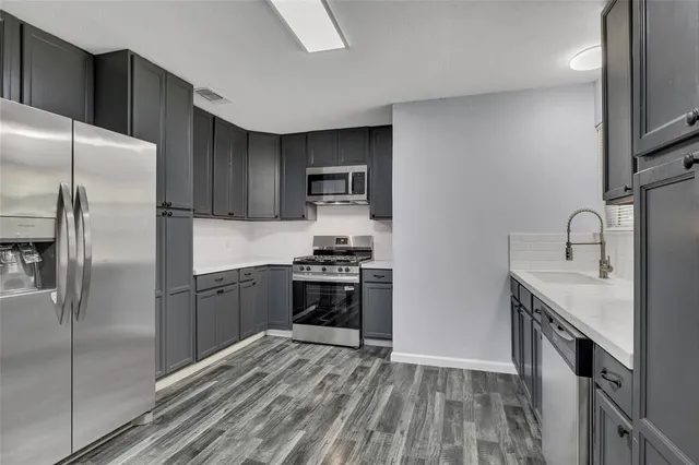 a kitchen with stainless steel appliances granite countertop a refrigerator a sink a stove and oven