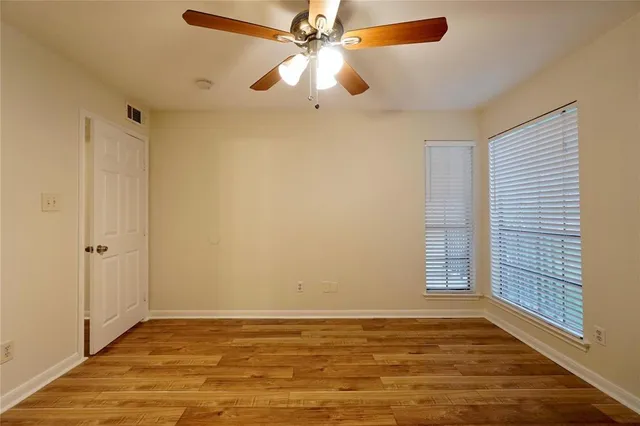 a view of an empty room with window and wooden floor