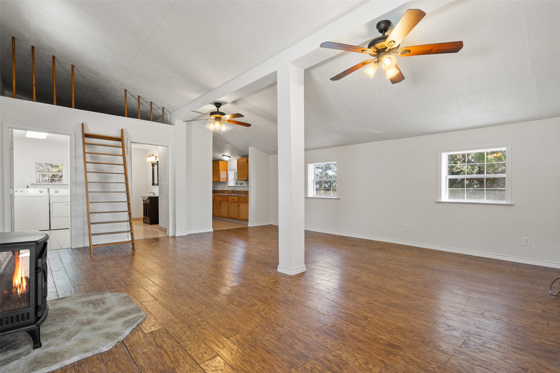 1401 Pursley Road Dripping Springs, TX 78620 - Photo 20 of 35 Guest house living room featuring ceiling fan, a wood stove, vaulted ceiling, dark wood-style flooring