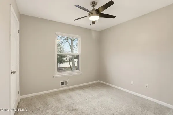 an empty room with a window and a fan